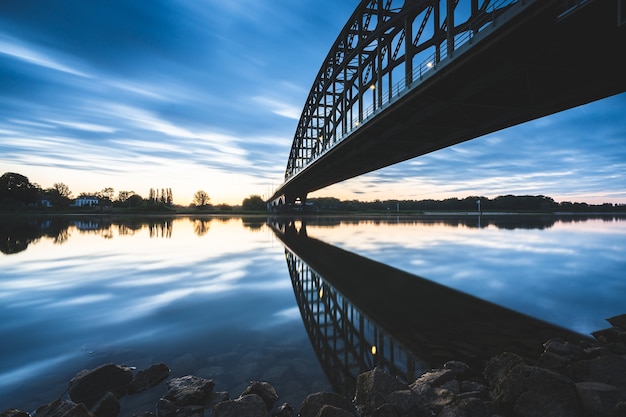 Stunning Bridge Reflection on a Serene Lake at Sunset – Free Download