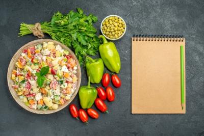 Top View of a Bowl of Vegetable Salad with Notepad on a Dark Green Table – Free to Download