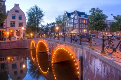 Nederlandse stenen brug met drie bogen op het Amsterdamse kanaal met vele geparkeerde fietsen – Gratis download van stockfoto’s