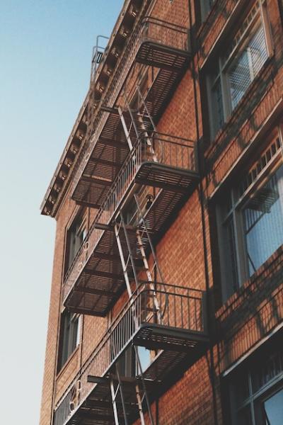 Vertical Low-Angle Shot of an Old Brick Building with an Emergency Exit Staircase – Free to Download