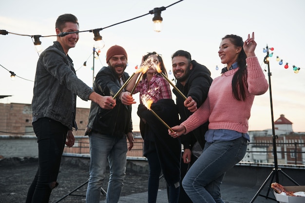 Group of Young Beautiful Friends Playing with Sparklers on the Rooftop – Free Download