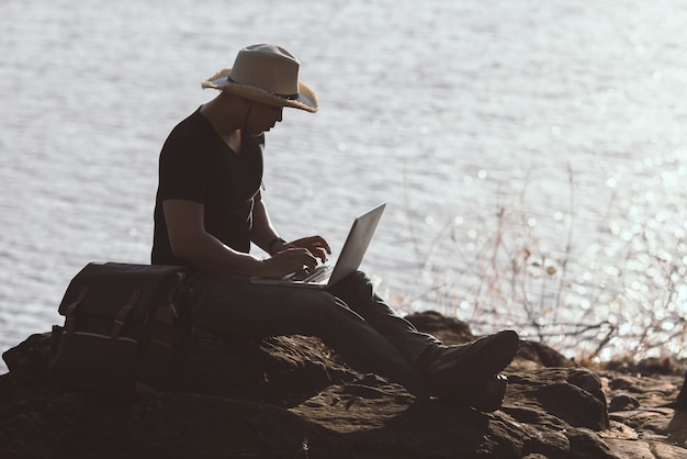 Backpacker Relaxing on the Mountain with a Laptop – Free Download