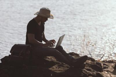 Backpacker Relaxing on the Mountain with a Laptop – Free Download