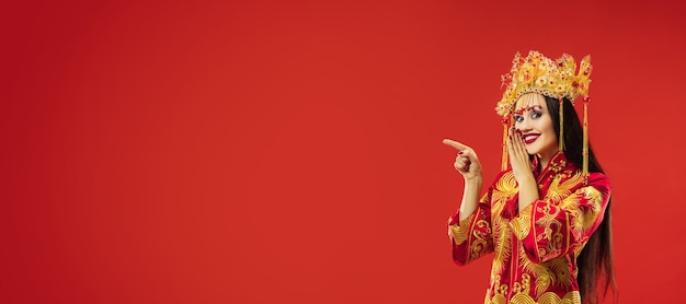 Traditional Chinese Woman Posing Gracefully in Studio with Red Wall – Free Download