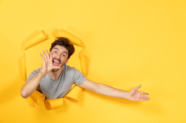 Young Male Peering Through Torn Yellow Paper Surface – Free Stock Photo, Download Free