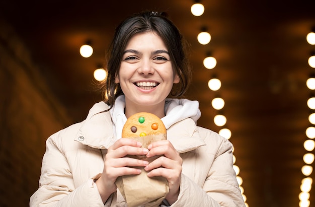 Attractive Young Woman Enjoying Gingerbread with a Bokeh Background – Free Download