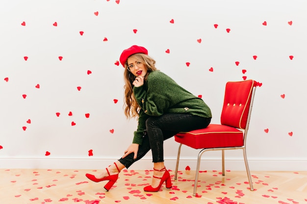 Carefree Woman in Soft Green Shirt Sitting in Red Chair – Free Stock Photo for Download