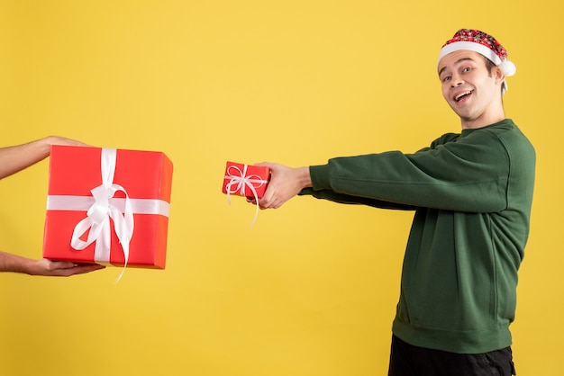 Young Man Exchanging Gifts with Female Hand on Yellow Background – Free Stock Photo, Download Free