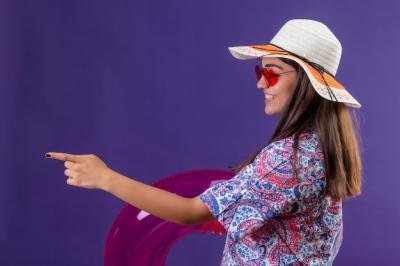 Beautiful Woman in Summer Hat and Red Sunglasses Cheerfully Pointing with Inflatable Ring – Free Download