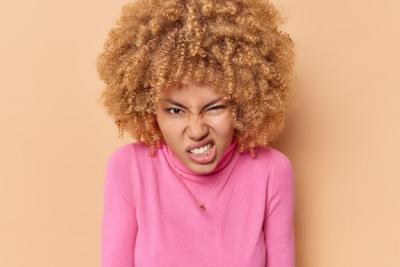 Irritated Young Woman with Curly Hair and Hateful Expression – Free Stock Photo for Download