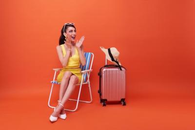 Beautiful Woman Relaxing on a Beach Chair with Suitcase Against a Summer Orange Background – Free Download