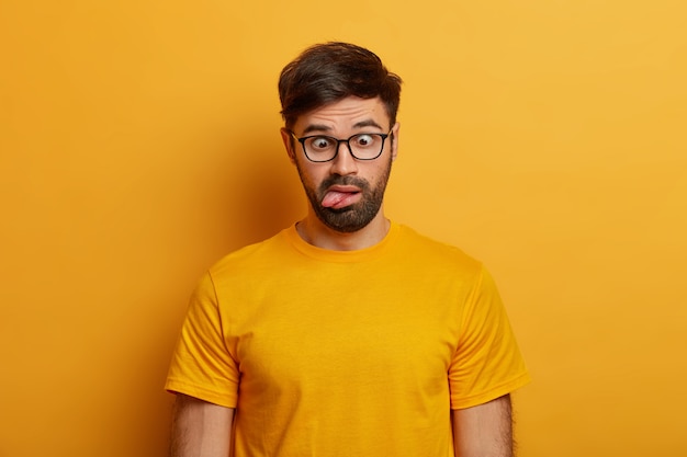 Bearded Guy Making Funny Faces Against a Yellow Wall – Free Stock Photo for Download