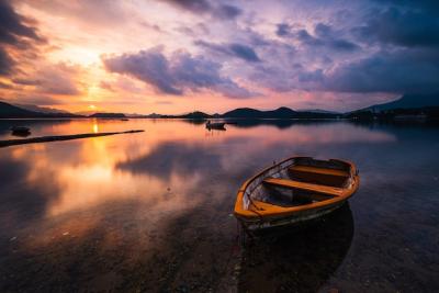 Serene Lake View with Wooden Rowboat and Dramatic Clouds â Free Download