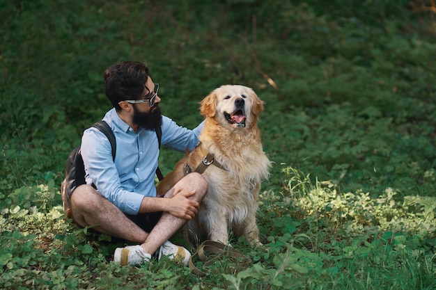 Man Sitting Cross-Legged on Grass with His Dog – Free to Download