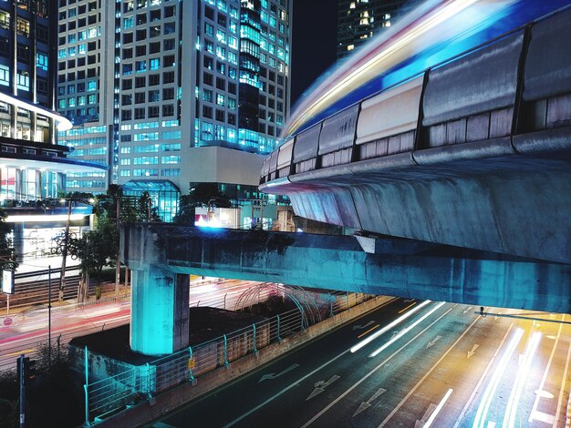 Light Trails on Road Amidst City Buildings at Night – Free Download