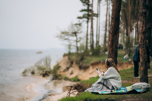 A young woman sitting by a serene lake in a forest – free to download