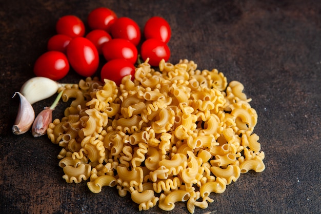 Macaroni with Tomatoes and Garlic on Dark Textured Background – Free Download