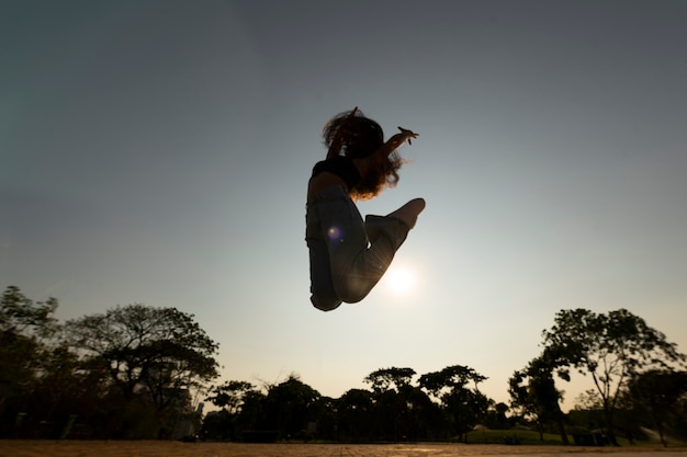 Woman Silhouette Jumping at Sunset – Free Download