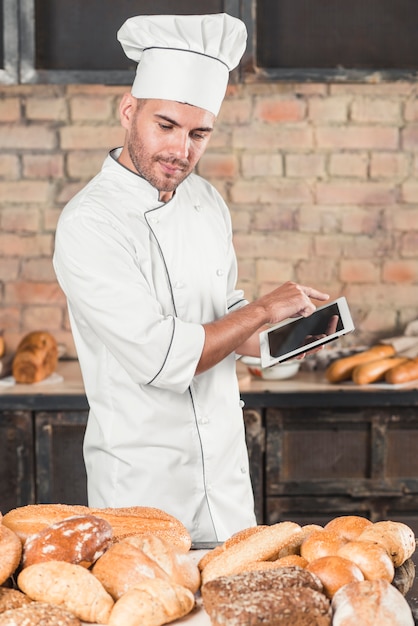 Male Baker Reviewing Assortment of Breads with Digital Tablet – Free Download