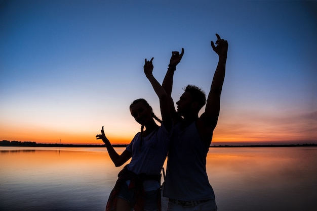 Young Couple Silhouettes at Sunrise by the Lake – Free Download