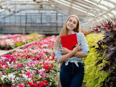 Smiley Woman in Greenhouse with Clipboard – Free Download