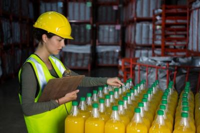 Female Worker Inspecting Juice Bottles – Free Download