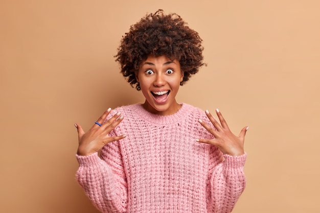 Cheerful Woman Smiling with Surprise Against Brown Studio Wall – Free Download