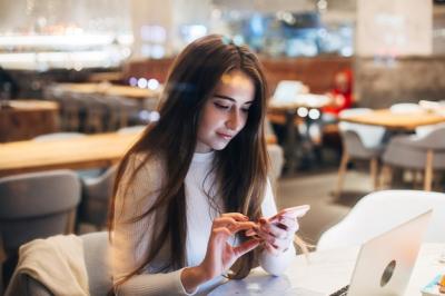 Cute and Pretty Young Woman Using Smartphone in Cafe – Free Download