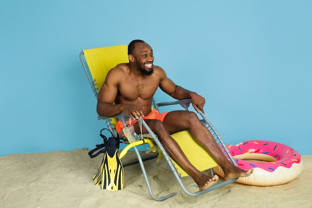 Happy Young Man Laughing with Beach Ring on Blue Studio Background – Free Download