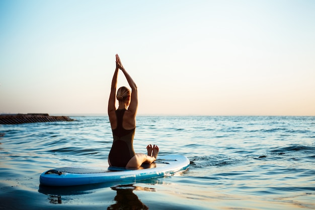 Beautiful Woman Practicing Yoga on Surfboard at Sunrise – Free Download