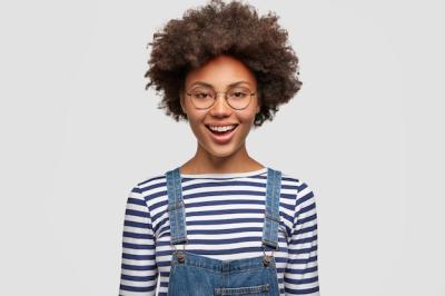 Cheerful Black Woman Celebrating Project Success in Casual Striped Sweater and Denim Overalls – Free Stock Photo for Download