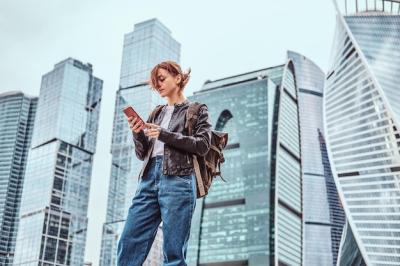 Trendy Redhead Student with Tattoos Using Smartphone in Moscow’s Skyscrapers – Free Download