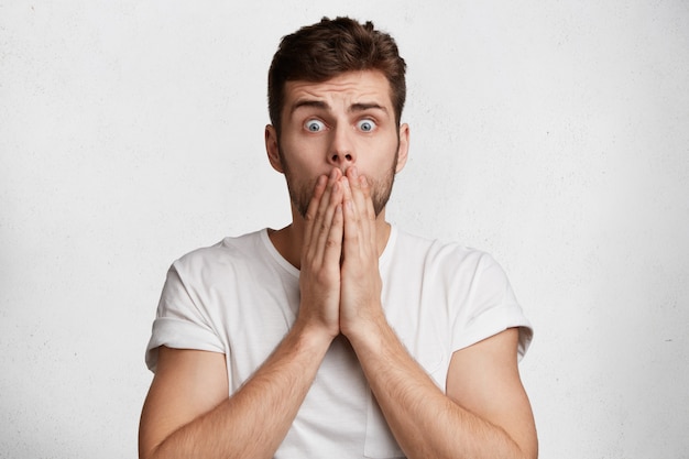 Handsome Terrified Male Covers Mouth, Shocked by Something Awful – Free Download