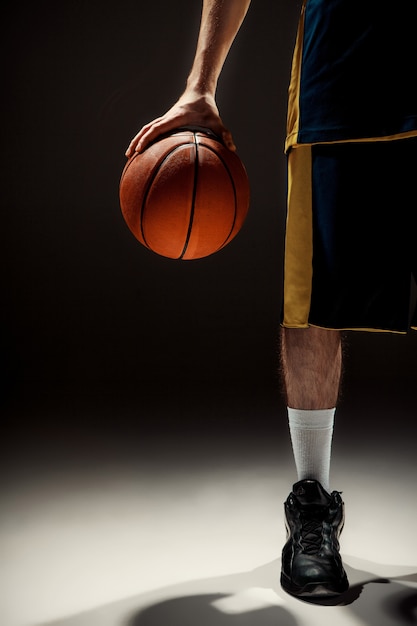 Silhouette View of a Basketball Player Holding a Basketball on Black Background – Free to Download