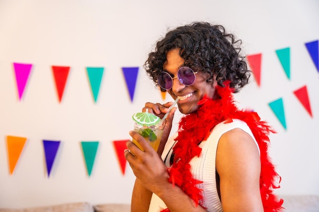 Gay Man Enjoying a Cocktail Surrounded by Colorful Garlands – Free Download