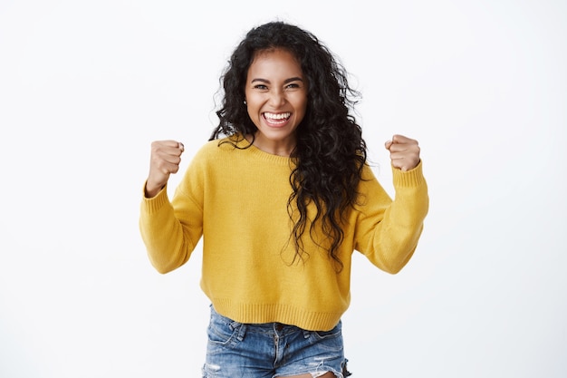 Cute Woman in Yellow Sweater Celebrating Victory with Fist Pump – Free Stock Photo for Download