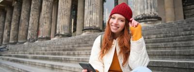 Young Urban Girl in Red Hat Sits on Stairs Near Museum with Mobile Phone – Free Download