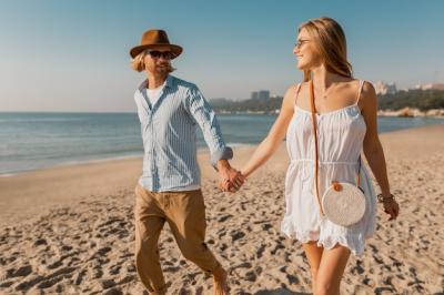 Young Man in Hat and Blonde Woman in White Dress Running on Beach – Free Download