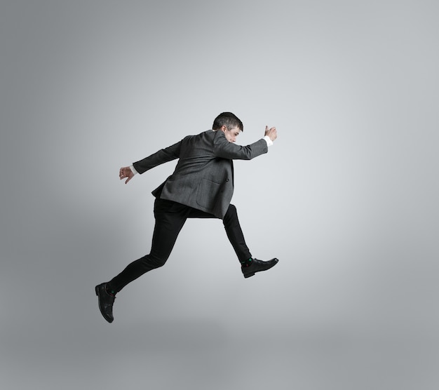 Caucasian Man in Office Clothes Running Isolated on Grey Wall – Free Download