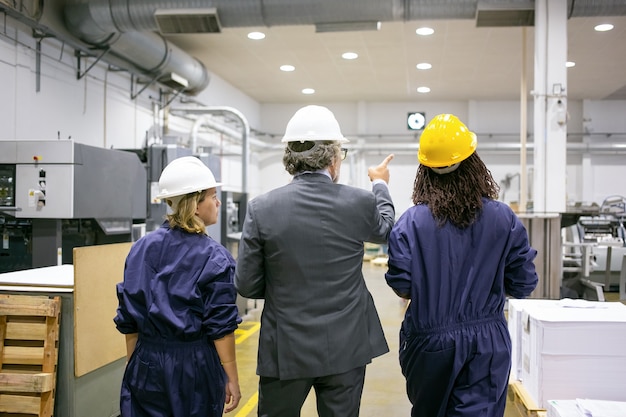 Male Engineer and Female Factory Workers in Hardhats Discussing Equipment – Free to Download