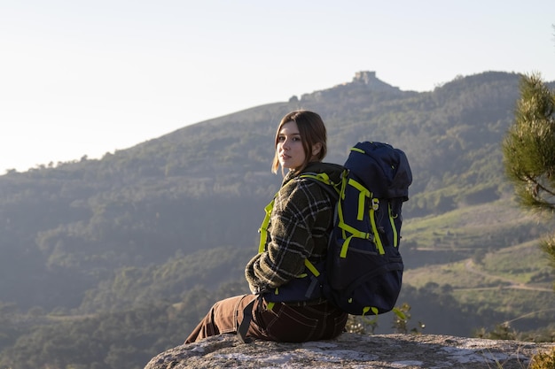 Happy Young Female Backpacker Sitting on a Stone – Free Stock Photo Download