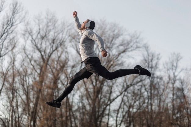 Lateral View of a Sporty Man Jumping in a Forest – Free Download