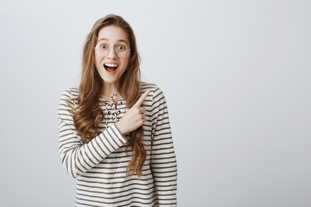 Excited and Impressed Girl Pointing Upper Right Corner – Free Stock Photo for Download