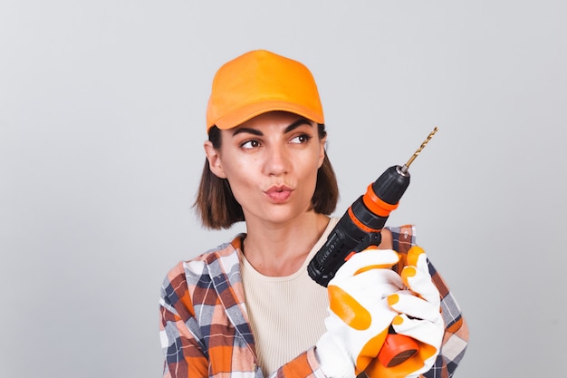 Confident Woman in Plaid Shirt and Hat Holding a Drill for Home Repairs – Free Download