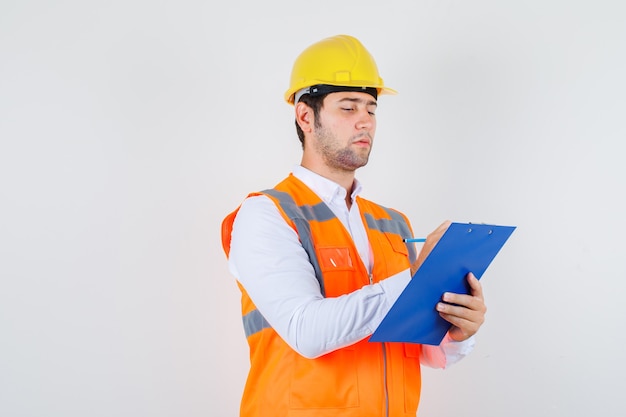 Builder Man Taking Notes on Clipboard in Uniform – Free Stock Photo for Download