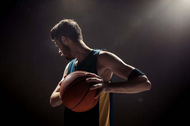 Silhouette of a Basketball Player on a Black Wall – Free Download