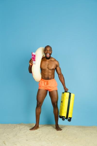 Happy Young Man Relaxing with Beach Ring and Bag – Free Stock Photo for Download