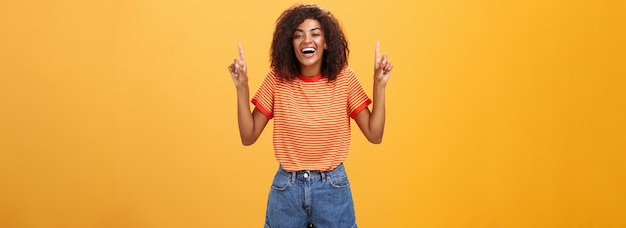 Portrait of a Joyful African American Girl Laughing Against an Orange Wall – Free Download