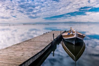 Boat Docked by Wooden Pier Reflecting in Cloudy Sea â Free Download