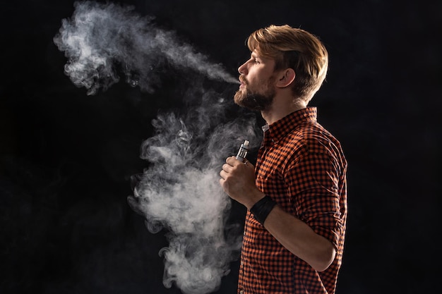 Young Man with Beard and Stylish Hairstyle Smoking in Studio – Free Stock Photo for Download